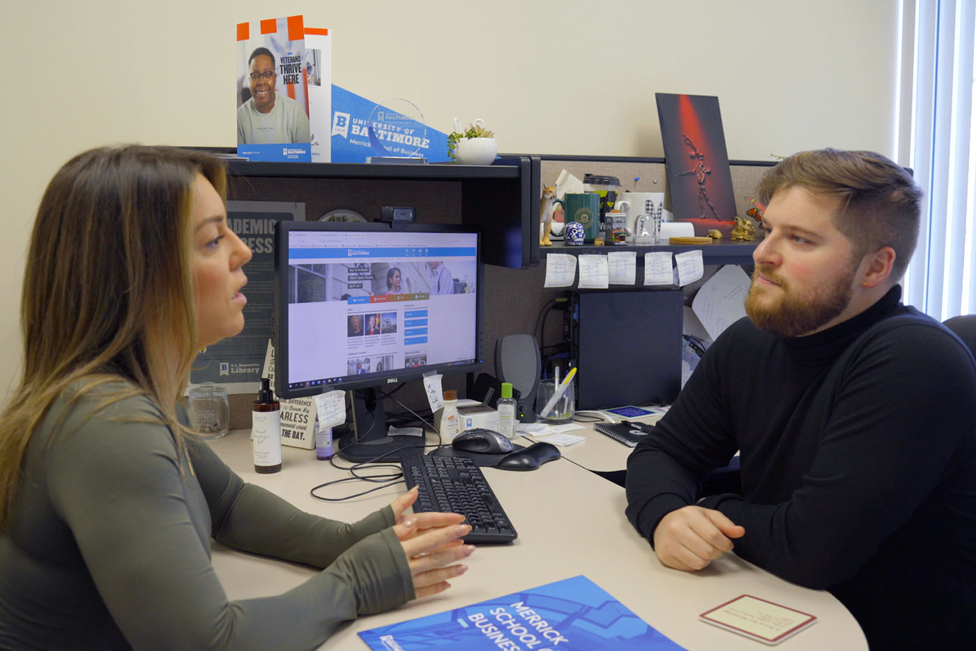 A female student meets with a male adviser in an office.